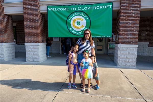 a family smiling under a welcome to clovercroft sign